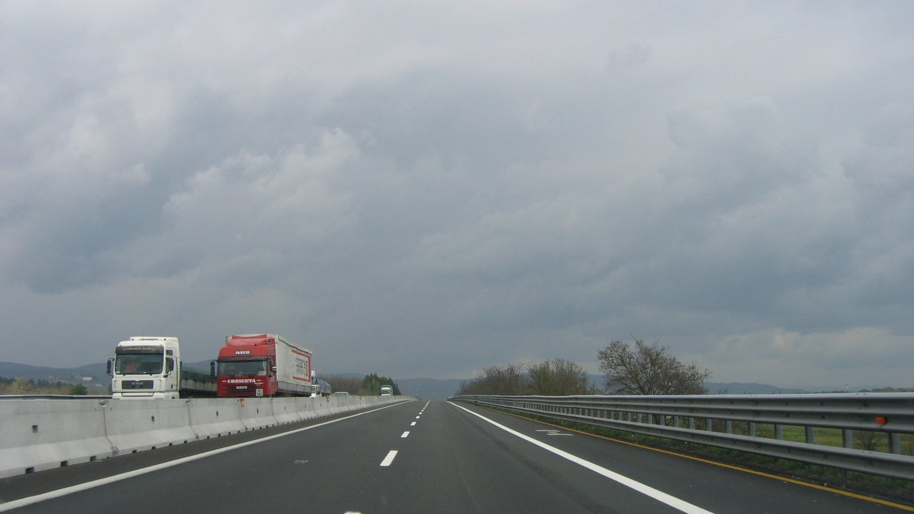 Stand-in photo from 2006, not of this week’s protests: two trucks, one white and one red, on the A1 motorway near Arezzo, Italy, under a grey, cloudy sky