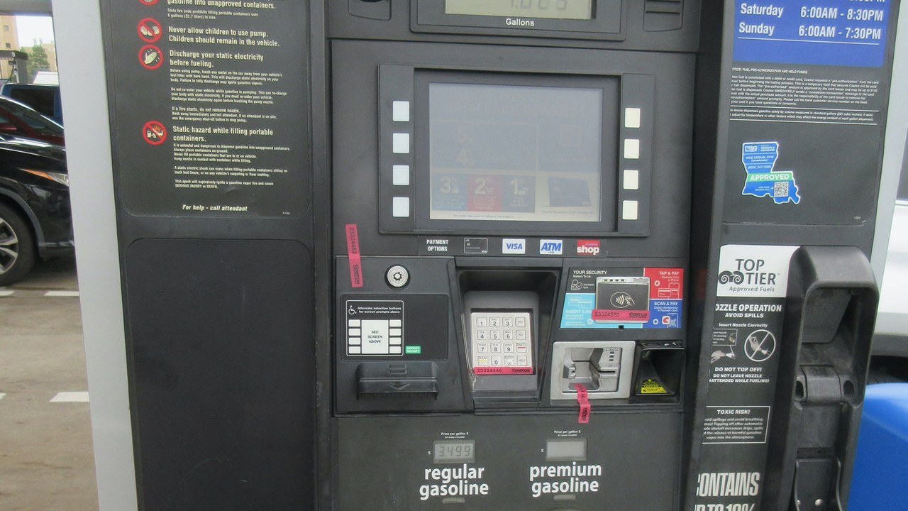 Stand-in, not a photo of this event: a Costco gas pump in New Orleans showing yellow Regular and Premium price panels and pump handles under a white canopy, with cars and a Costco building behind it (June 2026)