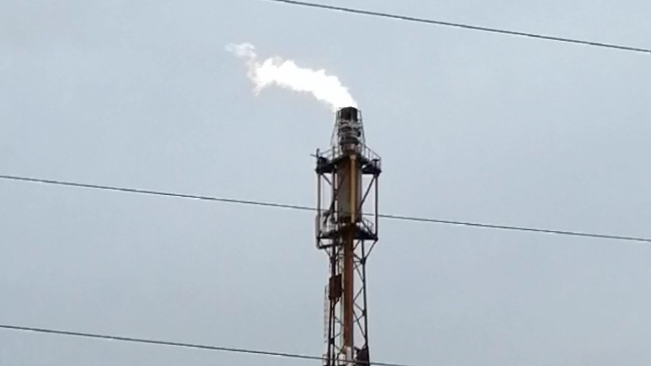 Stand-in, not a photo of this event: an orange lattice flare stack at the Ryazan oil refinery sends a white plume into a grey sky, with power lines across the frame, photographed in October 2020
